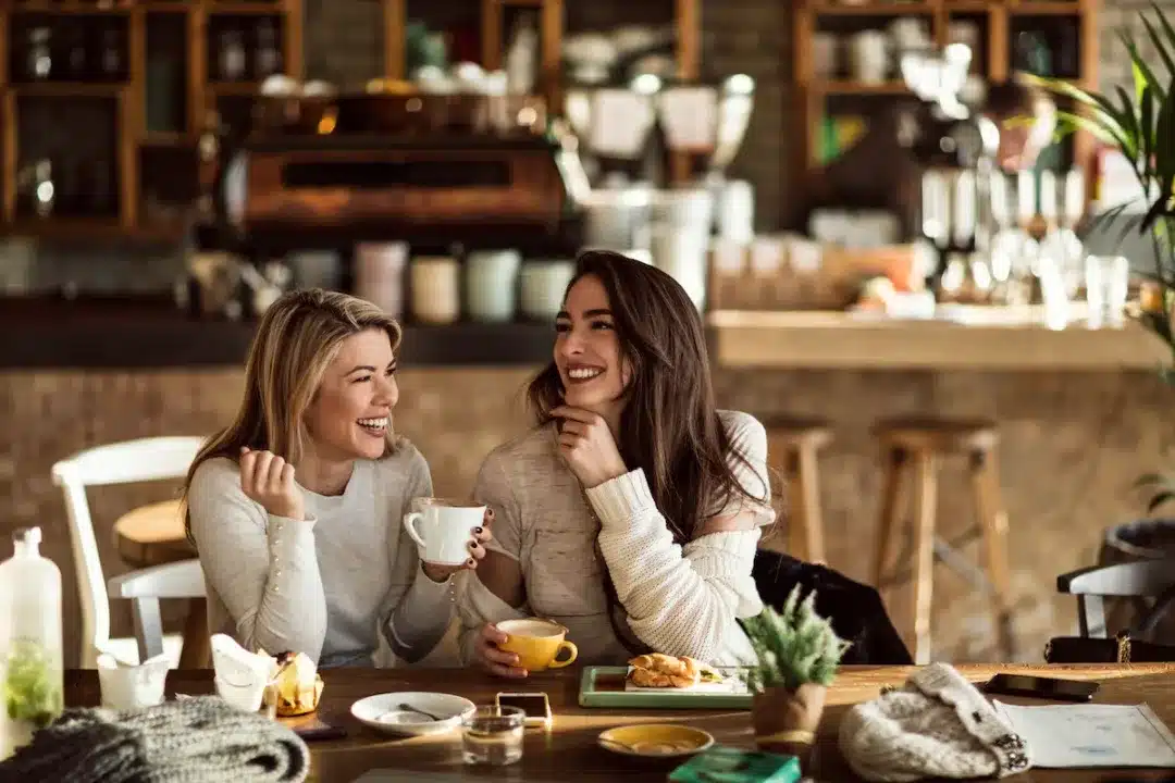 Young,Happy,Women,Talking,And,Laughing,While,Drinking,Coffee,Together