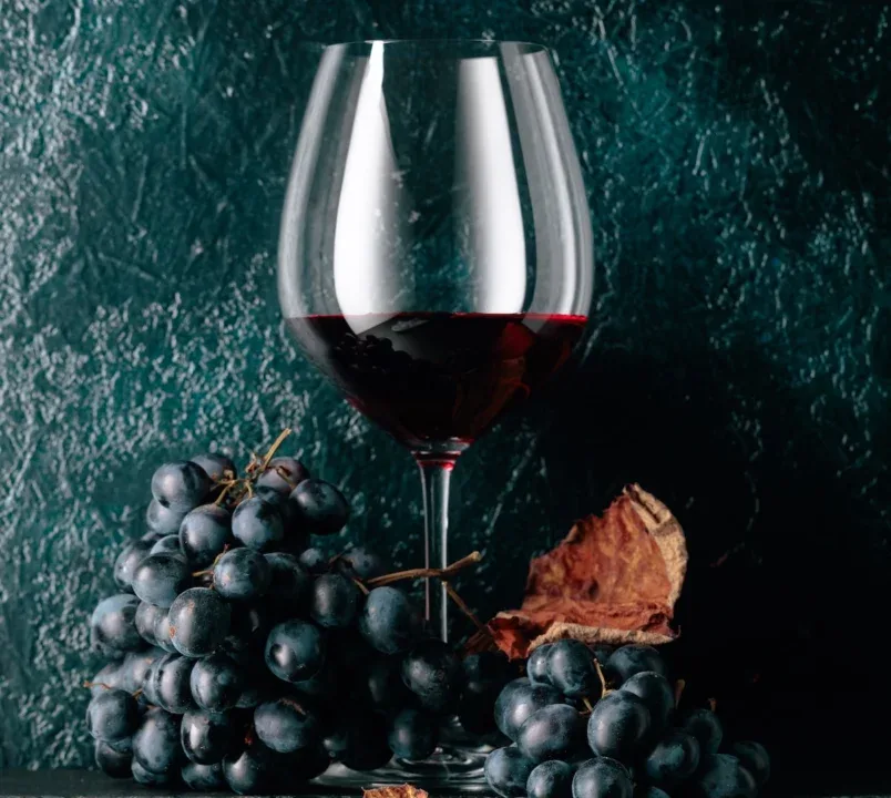 Glass,Of,Red,Wine,And,Blue,Grapes,With,Dried,Up