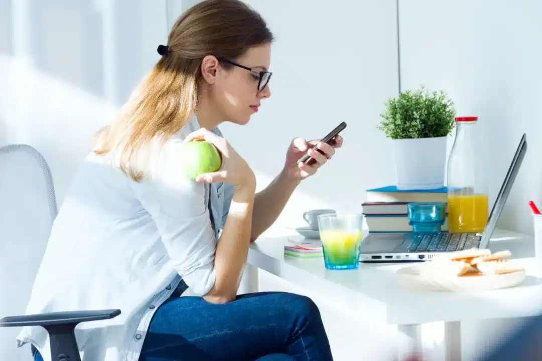 Portrait,Of,Pretty,Young,Woman,Eating,An,Apple,And,Working